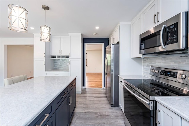 25 Nottingham Dr, Hempfield Twp, PA 15601 - kitchen featuring appliances with stainless steel finishes, white cabinets, light wood-type flooring, decorative backsplash, and hanging light fixtures