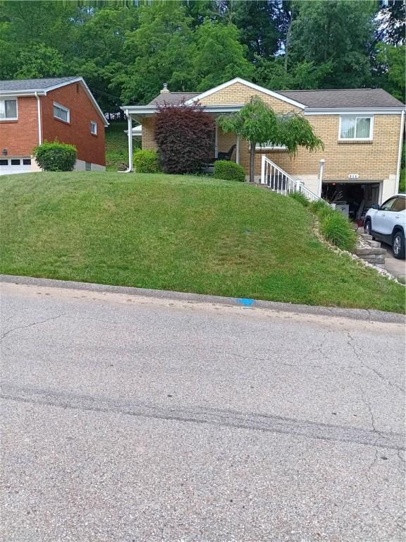 914 Woodland Ave, Port Vue, PA 15133 - single story home featuring a garage, a front lawn, and view of wooded area