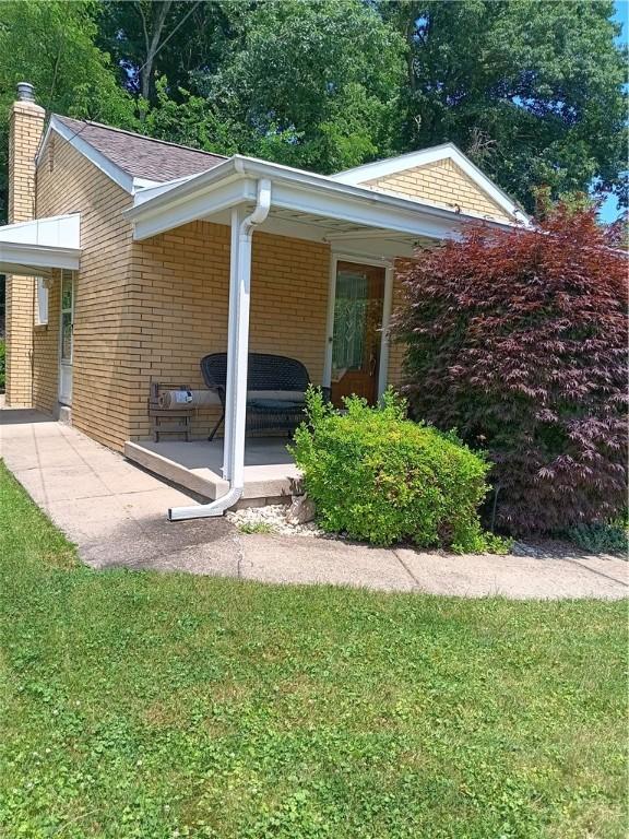 914 Woodland Ave, Port Vue, PA 15133 - view of home's exterior featuring brick siding, a chimney, and a yard