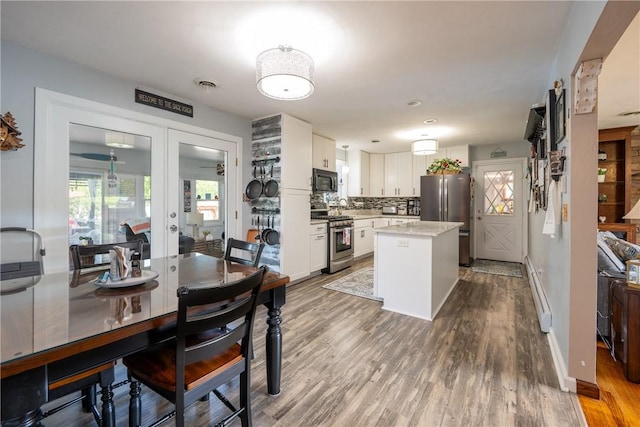 164 Seger Rd, Derry Twp, PA 15627 - kitchen featuring appliances with stainless steel finishes, white cabinetry, tasteful backsplash, wood finished floors, and a kitchen island