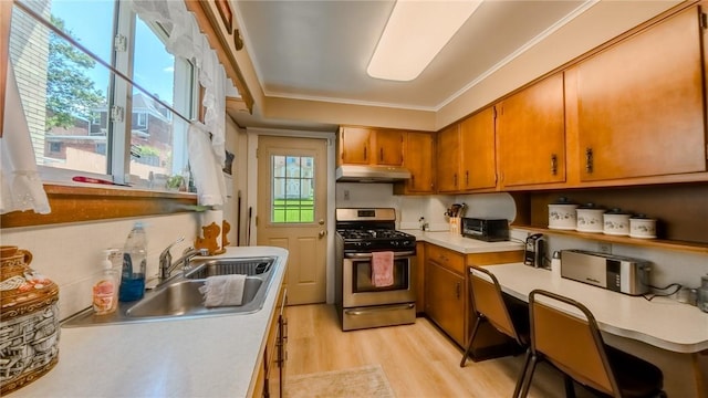 426 Saint Joseph St, Mount Oliver, PA 15210 - kitchen with gas stove, under cabinet range hood, brown cabinetry, light wood finished floors, and crown molding