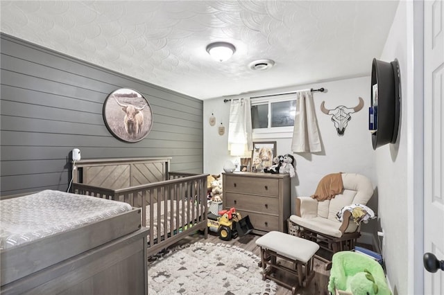 476 Trees Mills Rd, Salem Twp, PA 15601 - bedroom with wood finished floors, wooden walls, and a crib