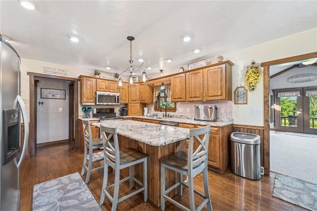 227 Holly Pl, Mount Pleasant Twp Wml, PA 15666 - kitchen featuring stainless steel appliances, brown cabinets, a wainscoted wall, dark wood-type flooring, and a center island