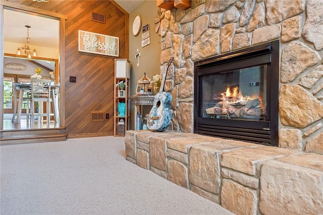 227 Holly Pl, Mount Pleasant Twp Wml, PA 15666 - carpeted living area featuring wooden walls, a stone fireplace, and a chandelier