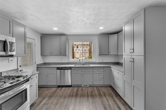 16 4th St, Sharpsburg, PA 15215 - kitchen featuring stainless steel appliances, gray cabinetry, dark wood-style flooring, light stone countertops, and a textured ceiling