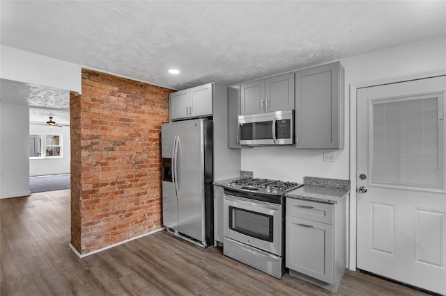 16 4th St, Sharpsburg, PA 15215 - kitchen featuring appliances with stainless steel finishes, gray cabinetry, dark wood-style floors, ceiling fan, and brick wall