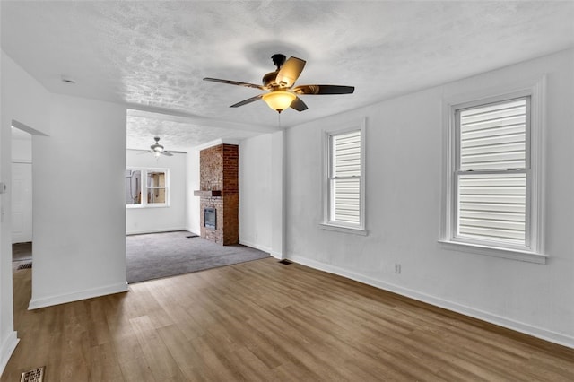 16 4th St, Sharpsburg, PA 15215 - unfurnished living room featuring ceiling fan, wood finished floors, a textured ceiling, and a brick fireplace