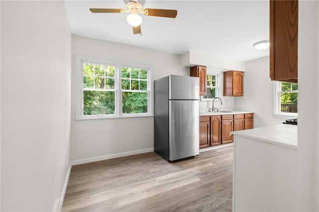 125 Carroll St, Aliquippa, PA 15001 - kitchen featuring freestanding refrigerator, brown cabinetry, light countertops, light wood finished floors, and healthy amount of natural light