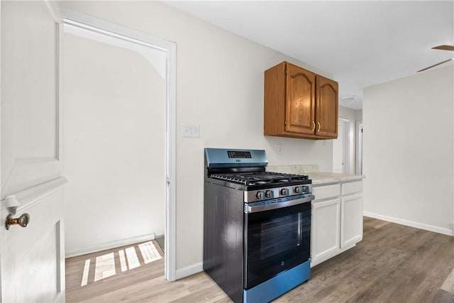 125 Carroll St, Aliquippa, PA 15001 - kitchen featuring stainless steel range with gas stovetop, light wood-style flooring, light countertops, a ceiling fan, and brown cabinets