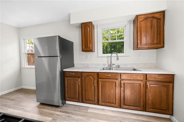 125 Carroll St, Aliquippa, PA 15001 - kitchen featuring freestanding refrigerator, brown cabinetry, light wood finished floors, and light countertops