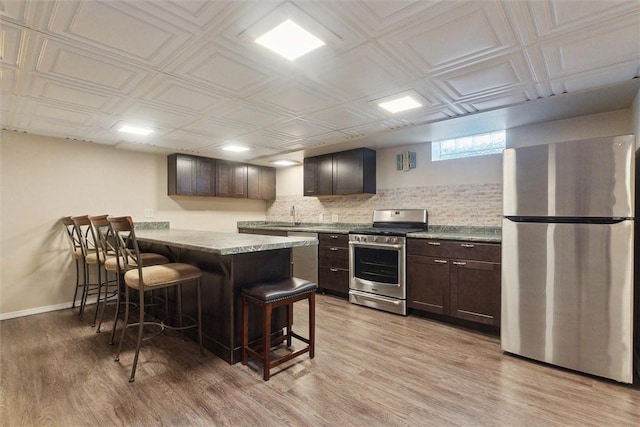 410 Blackhawk Rd, Chippewa Twp, PA 15010 - kitchen featuring stainless steel appliances, a kitchen bar, dark brown cabinets, and light wood-style flooring