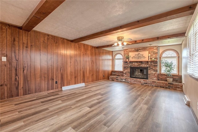 1318 Dellview Dr, Unity Twp, PA 15601 - unfurnished living room featuring wood finished floors, beamed ceiling, healthy amount of natural light, ceiling fan, and a brick fireplace