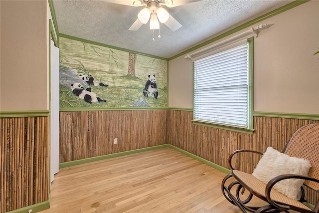 1318 Dellview Dr, Unity Twp, PA 15601 - living area featuring wainscoting, wood finished floors, a ceiling fan, wooden walls, and a textured ceiling