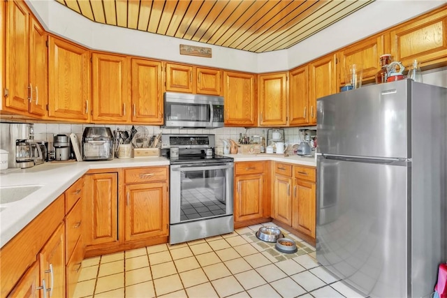 530 Perry Hwy, Lancaster Twp, PA 16037 - kitchen with appliances with stainless steel finishes, light countertops, backsplash, brown cabinetry, and light tile patterned floors