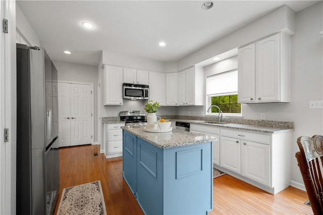 6412 Interlaken Dr, South Fayette, PA 15057 - kitchen with appliances with stainless steel finishes, white cabinetry, light wood finished floors, light stone countertops, and a kitchen island