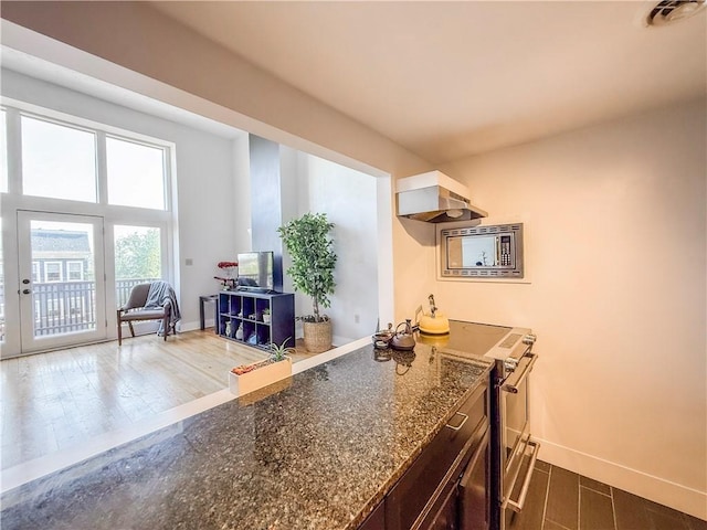 66 Pius St Unit 103, South Side, PA 15203 - kitchen with stainless steel appliances, dark wood-style floors, wall chimney exhaust hood, and dark stone countertops