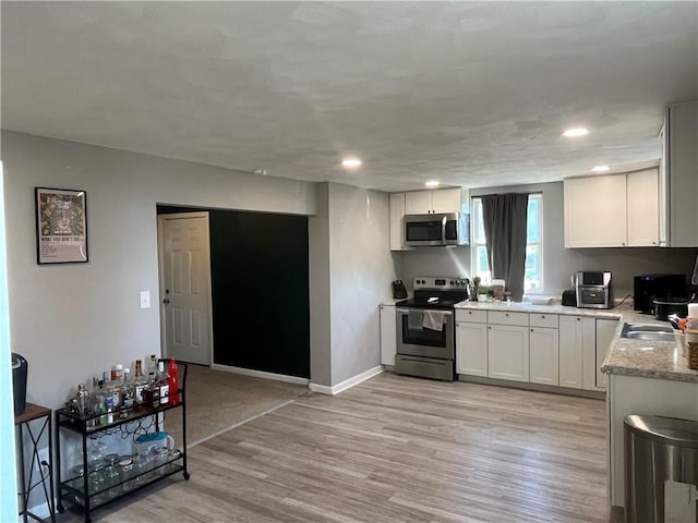 2103 Vermont Ave, West Mifflin, PA 15122 - kitchen featuring appliances with stainless steel finishes, light wood finished floors, white cabinetry, light stone countertops, and recessed lighting