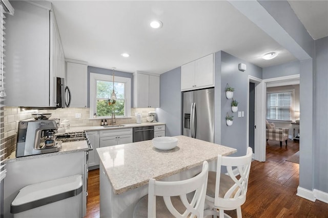 727 Vermont Ave, Mt Lebanon, PA 15234 - kitchen with appliances with stainless steel finishes, decorative backsplash, a kitchen island, dark wood-type flooring, and a breakfast bar area