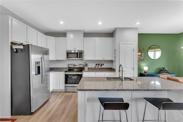 1006 Callaway Dr, Jeannette, PA 15644 - kitchen with appliances with stainless steel finishes, a kitchen breakfast bar, dark stone counters, white cabinetry, and recessed lighting