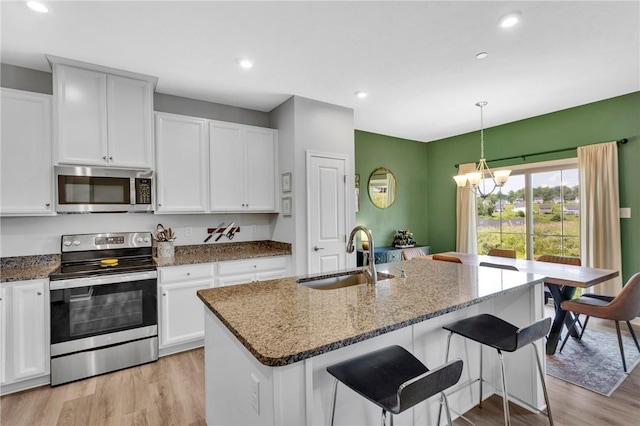 1006 Callaway Dr, Jeannette, PA 15644 - kitchen with stainless steel appliances, a chandelier, light wood-type flooring, dark stone countertops, and white cabinets