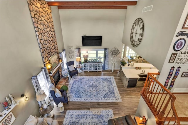 245 Shaw Ct, Salem Twp Wml, PA 15670 - living area featuring a towering ceiling, beamed ceiling, wood finished floors, a stone fireplace, and stairway