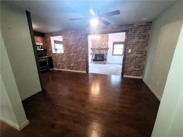 314 Wren Dr, Hempfield Twp Wml, PA 15601 - unfurnished living room featuring ceiling fan, dark wood-style flooring, a stone fireplace, and brick wall