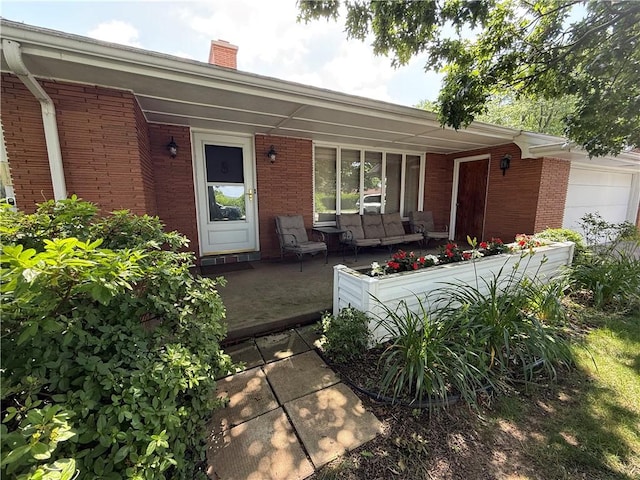 1180 Sunset Dr, Latrobe, PA 15650 - property entrance with covered porch, brick siding, a chimney, and a garage