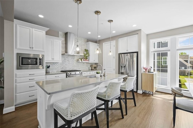 2123 Westcott Ln, South Fayette, PA 15017 - kitchen featuring appliances with stainless steel finishes, wall chimney range hood, a breakfast bar, a center island with sink, and backsplash