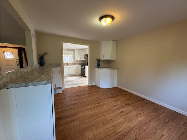 111 Hemlock Ln, Monroeville, PA 15146 - kitchen with stove, white cabinetry, light wood-style floors, and stainless steel microwave