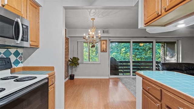 6108 Sanlin Dr, Moon/Crescent Twp, PA 15108 - kitchen featuring stainless steel microwave, electric range, tile counters, a chandelier, and light wood-style flooring