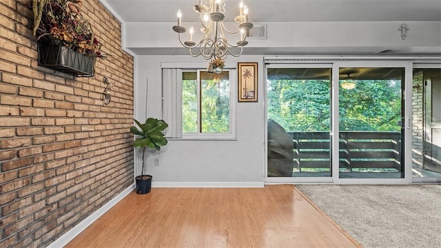 6108 Sanlin Dr, Moon/Crescent Twp, PA 15108 - unfurnished dining area featuring a chandelier, wood finished floors, and brick wall