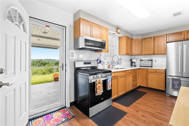 1434 Washington Blvd, Port Vue, PA 15133 - kitchen featuring appliances with stainless steel finishes, light countertops, light wood-style flooring, and tasteful backsplash
