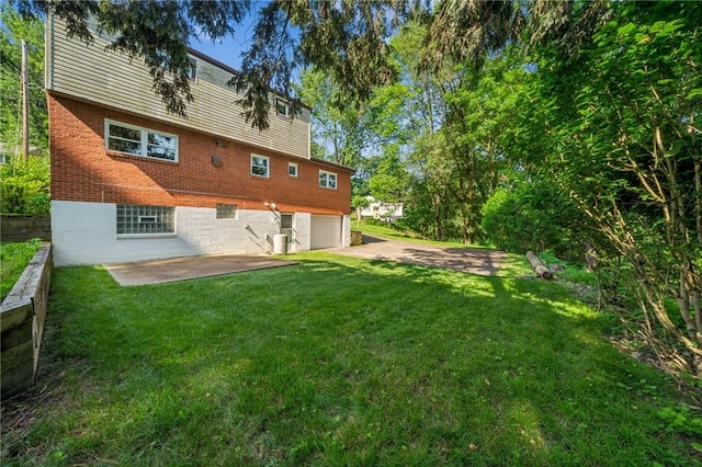 172 Fox Chase Dr, Penn Hills, PA 15147 - back of house featuring an attached garage, a lawn, brick siding, a patio, and driveway