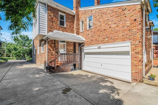 6403 Beacon St, Squirrel Hill, PA 15217 - view of front of house featuring concrete driveway, a garage, brick siding, and a chimney