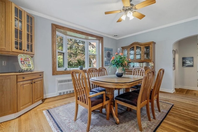 6403 Beacon St, Squirrel Hill, PA 15217 - dining area featuring radiator, arched walkways, light wood-style floors, ceiling fan, and crown molding
