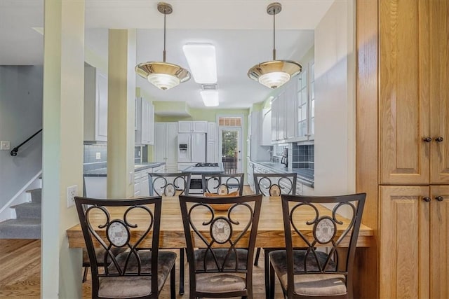 6403 Beacon St, Squirrel Hill, PA 15217 - kitchen featuring white fridge with ice dispenser, a breakfast bar, tasteful backsplash, and wood finished floors
