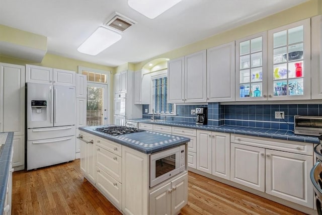 6403 Beacon St, Squirrel Hill, PA 15217 - kitchen with white appliances, white cabinetry, light wood finished floors, and tasteful backsplash
