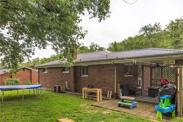 391 Wendel Rd, Pa, PA 15642 - rear view of property with a trampoline, a patio area, a yard, and brick siding