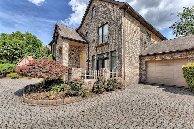 410 Lorenzo Ln, Hempfield Twp, PA 15642 - view of front of house with brick siding, decorative driveway, an attached garage, and a balcony