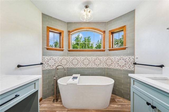 409 Park Rd, Bullskin Twp, PA 15683 - bathroom featuring vanity, tile walls, healthy amount of natural light, a soaking tub, and wood finished floors
