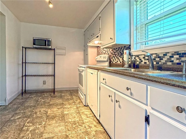 208 Beale Ave, Leechburg Boro, PA 15656 - kitchen with white appliances, backsplash, dark countertops, under cabinet range hood, and light stone finish floors