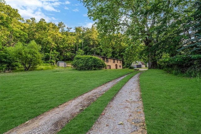 5028 W Smithfield St, Elizabeth Twp/Boro, PA 15135 - view of grassy yard with a storage shed, driveway, and a wooded view