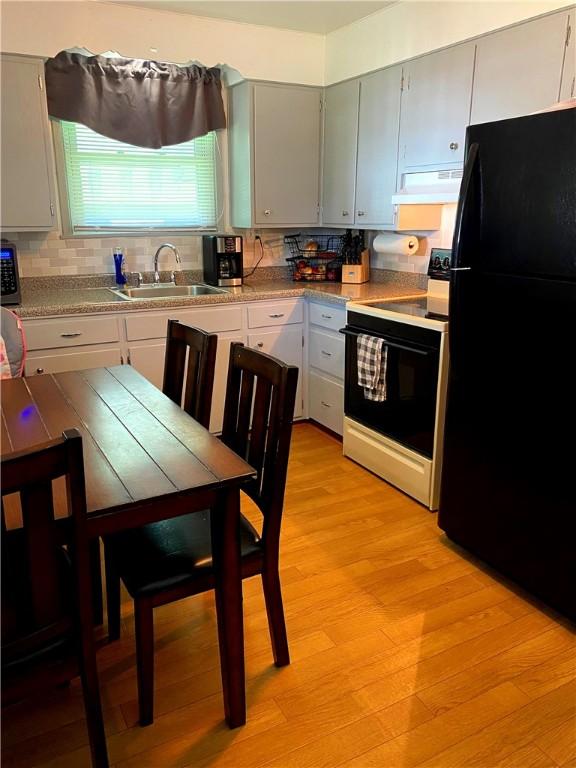 118 Delaware Ave, Scottdale, PA 15683 - kitchen with freestanding refrigerator, white range with electric cooktop, ventilation hood, and decorative backsplash