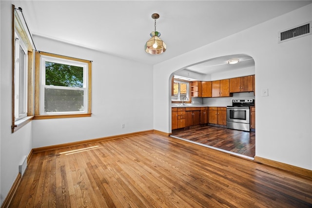 389 Mercer Rd, Hempfield Twp Mer, PA 16125 - kitchen with stainless steel range with electric cooktop, brown cabinets, dark wood-type flooring, and arched walkways