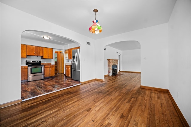 389 Mercer Rd, Hempfield Twp Mer, PA 16125 - kitchen featuring stainless steel appliances, brown cabinets, a stone fireplace, dark wood-type flooring, and decorative light fixtures