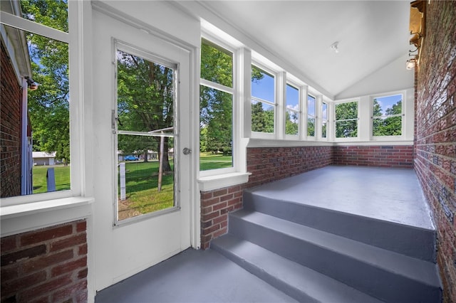 389 Mercer Rd, Hempfield Twp Mer, PA 16125 - unfurnished sunroom featuring brick wall, finished concrete flooring, and vaulted ceiling