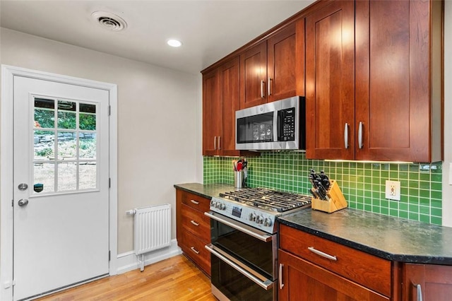 234 Orchard Dr, Mt Lebanon, PA 15228 - kitchen with appliances with stainless steel finishes, radiator heating unit, light wood finished floors, tasteful backsplash, and recessed lighting