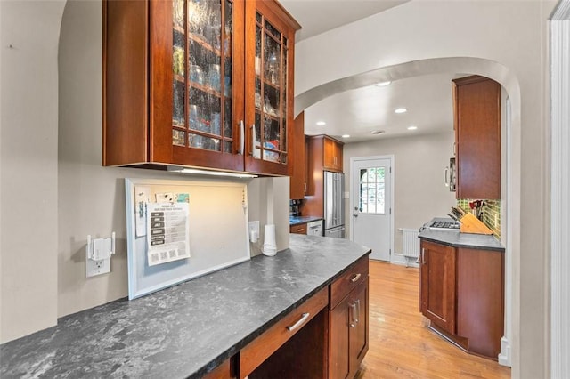 234 Orchard Dr, Mt Lebanon, PA 15228 - kitchen featuring arched walkways, dark countertops, freestanding refrigerator, glass insert cabinets, and light wood finished floors