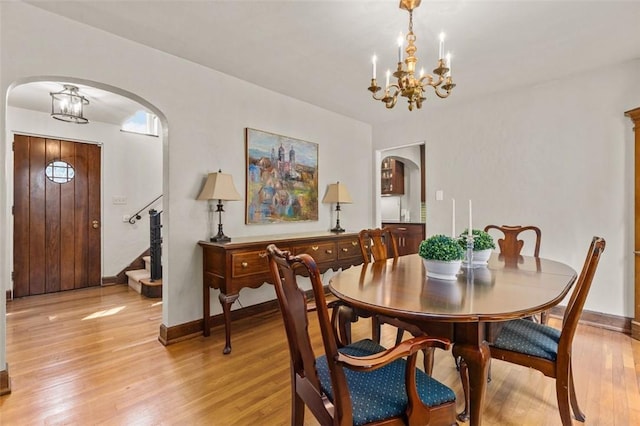 234 Orchard Dr, Mt Lebanon, PA 15228 - dining area with a chandelier, arched walkways, light wood finished floors, and stairs