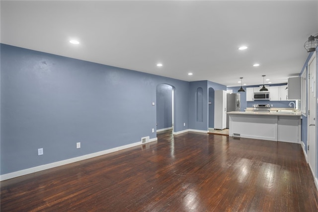 1809 Rosedale St, Verona, PA 15147 - unfurnished living room with arched walkways, dark wood finished floors, and recessed lighting
